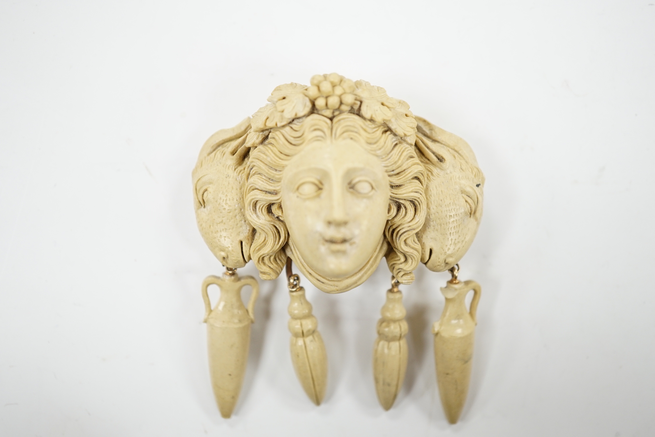 A yellow metal mounted lava drop brooch, modelled as the head of a lady flanked by ram's heads, width 53mm.